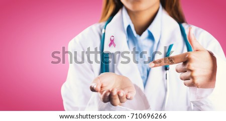 Mid section of female doctor showing empty hand against pink background