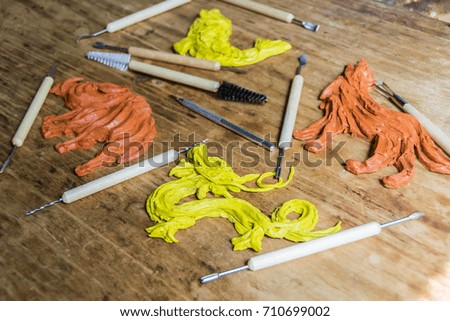 Figurine dragon, fish, wolf, boar
 clay plasticine in a workshop with tools on a wooden background
