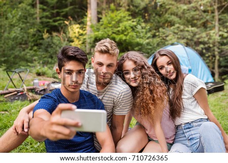 Teenagers in front of tent camping in forest.