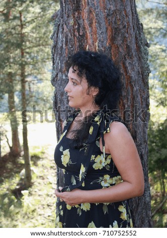 An outdoor photo session of an attractive young woman in a scene next to a tree, expressions
