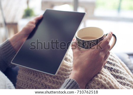 woman is drinking coffee and holding a tablet  at home Royalty-Free Stock Photo #710762518