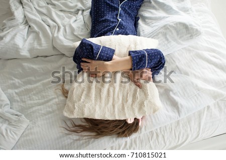 Too lazy to get out of bed, a woman covers her face with a pillow Royalty-Free Stock Photo #710815021