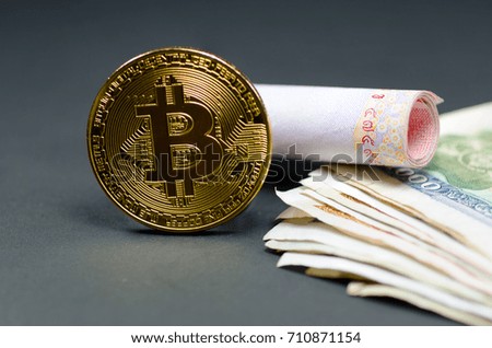 Photo of golden bitcoin (new virtual currency) with various banknote money as a background.