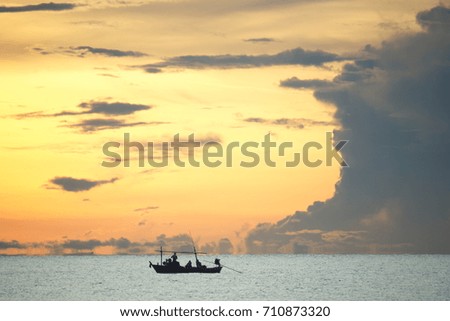 A small fishing boat catching fish with an orange background made very beautiful.