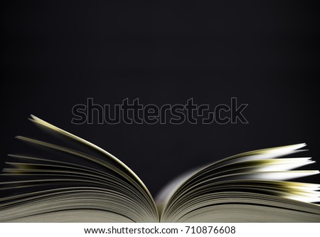 Open book with narrow depth of field on black background. Space for text above the book