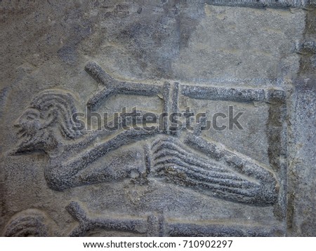 Egyptian Hieroglyphics. Man hog tied hanging from a stick in stone carving.