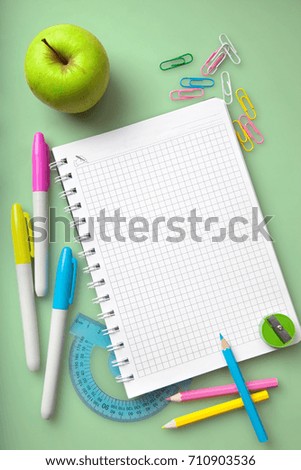 School supplies:notepad,colored markers and pencils,ruler, green apple lie on a green desk. The concept of school children's creativity in trendy colors.