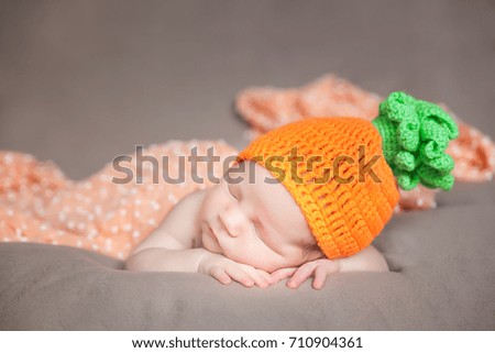 Sleeping newborn baby in a knitted carrot or pumpkin costume