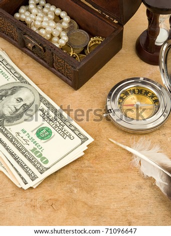 dollars, compass and hourglass on wood