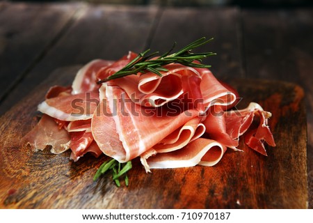 Italian prosciutto crudo or jamon with rosemary. Raw ham. Royalty-Free Stock Photo #710970187