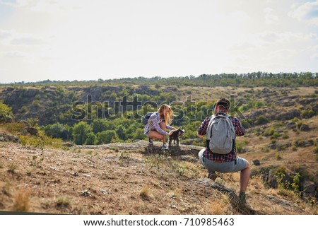 Photographer taking pictures of a beautiful girl outside. Tourist photo shooting on a natural background. Copy space.