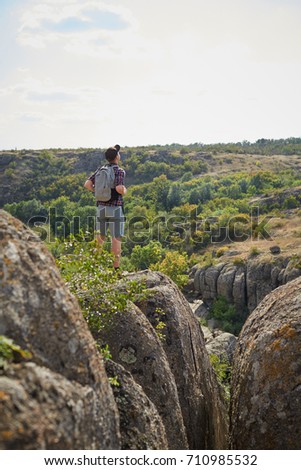 Young man with backpack looking into the distance on the top of mountains. A tourist on a natural background.