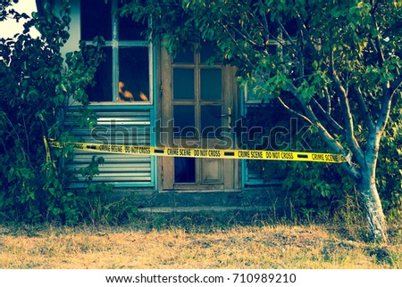 Crime scene tape near the house, police tape Do Not Cross outdoors