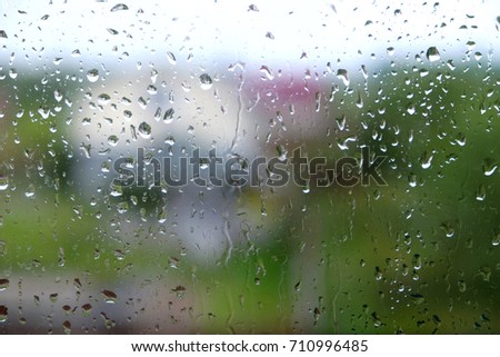 Dull landscape with many raindrops through house window on rainy autumn day 