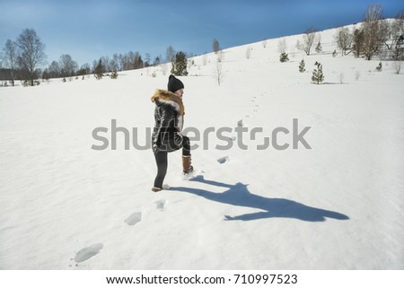 Girl walks on deep snowdrift. winter season and mountain landscape create the perfect mood. Smiling young woman in coat and fox fur collar. full length happy girl enjoying winter time season