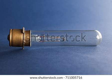 Vintage cinema lamp. Light bulb bronze surface on blue paper background, macro view shallow depth of field photo.