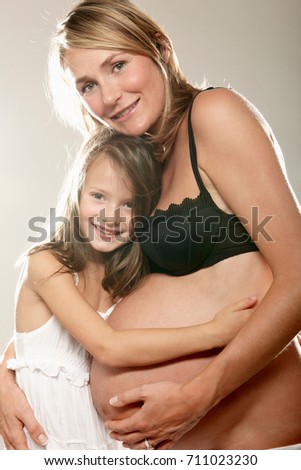 Pregnant woman with daughter, smiling