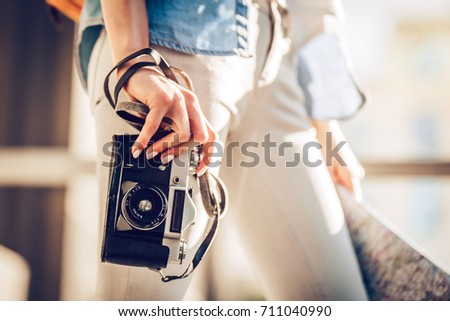 Cropped image of attractive young female tourist is exploring new city. Woman with retro camera in search of new adventures.