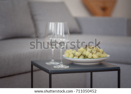 two empty glass wine glasses and white grapes on a wooden table, copy space