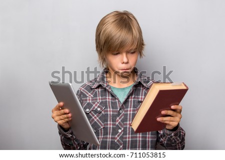 Ebook vs book. Boy holds book and tablet isolated over grey background. Technology, computer versus traditional print books concept