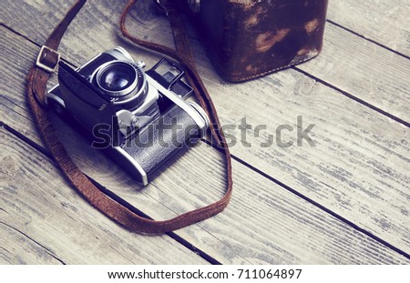 Old retro film analogue camera and belt bag (leather case) on vintage wooden boards. 