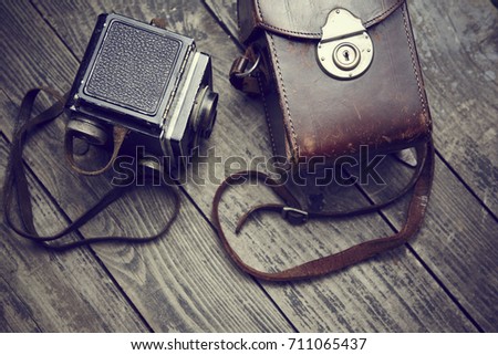 Old retro film twin lens reflex camera and belt bag (leather case) on vintage wooden boards. Focused to camera