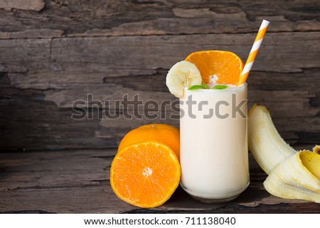 Orange and banana smoothies on a beautiful old wooden background.