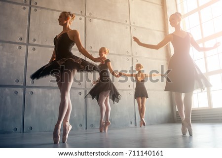 Four beautiful young Russian ballerinas in black packs, white pantyhose and ponts in the style of a black swan dance ballet in a black studio Royalty-Free Stock Photo #711140161