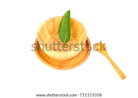 Green lemon leaves in wooden bowl on wooden dish with wooden spoon isolate on white background.
