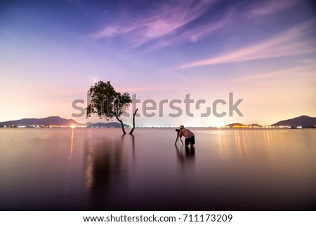 Silhouette of photographer taking picture of landscape during sunset, soft and select focus 
