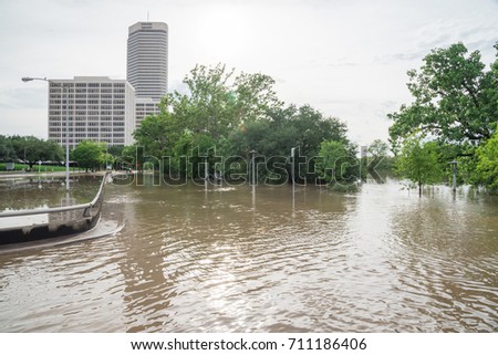 High and fast water rising in Bayou River from Montrose boulevard, Allen Parkway intersection with near town Houston in background, cloud sky. Heavy rain from Tropical Hurricane storm cause many flood