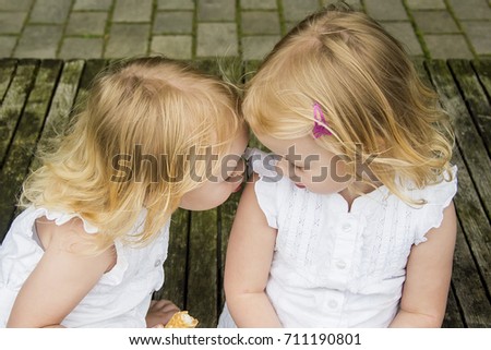 Twin girls eating ice cream and enjoying each other's company