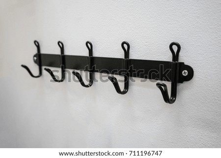 Black metal wall hanger mounted against white wall.
