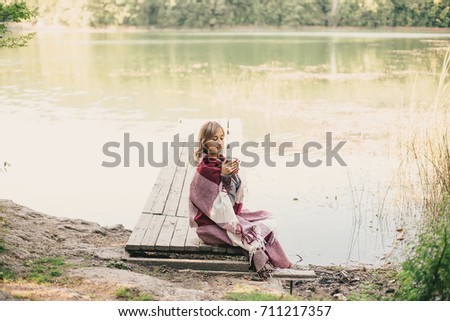 Young beautiful woman drinking cocoa near lake. Autumn mood