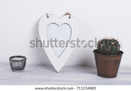 Photo frame with heart shape next to decoration objects on white and blue wooden table. Decor.