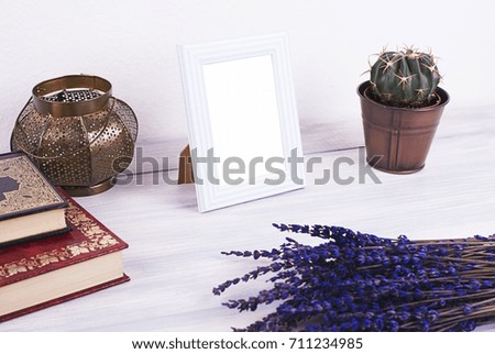 Photo frames next to decorative objects, books and lavender flower on white and blue wood table. Decor.