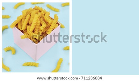 Uncooked italian pasta girandole on blue trendy background. Colorful diet and healthy food concept. Flat lay style with place for your text.