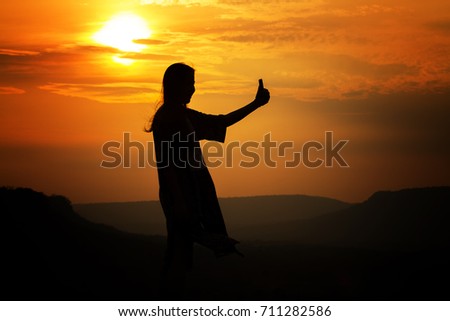 silhouette of Asian women photography and selfie with mountain at sunset .