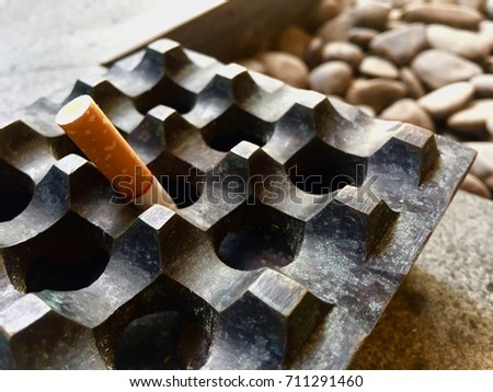 Cigarette Inside A Square Metal Ashtray  Royalty-Free Stock Photo #711291460
