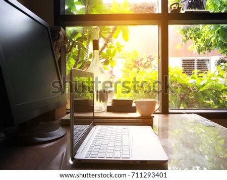 Businesses happen everywhere, just have inspiration. The picture of white laptop and a cup of coffee on wooden table near the window at home office. selective focus