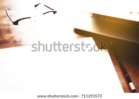 Businesses happen everywhere, just have inspiration. The picture of white laptop, hand, pencil and glasses on wooden table near the window at home office with sunshine effect. selective focus