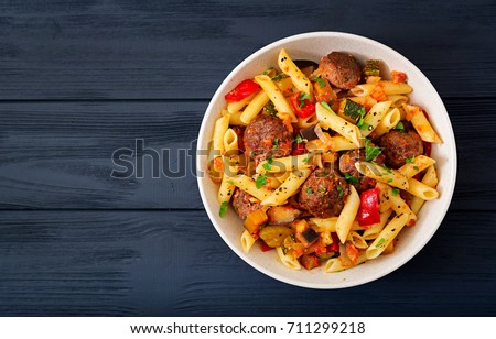 Penne pasta with meatballs in tomato sauce and vegetables in bowl. Top view. Flat lay Royalty-Free Stock Photo #711299218