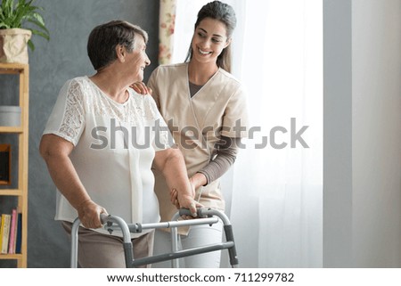 Smiling nurse helping senior lady to walk around the nursing home Royalty-Free Stock Photo #711299782