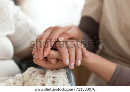 Close-up photo of a female caregiver and senior woman holding hands. Senior care concept. Royalty-Free Stock Photo #711300070