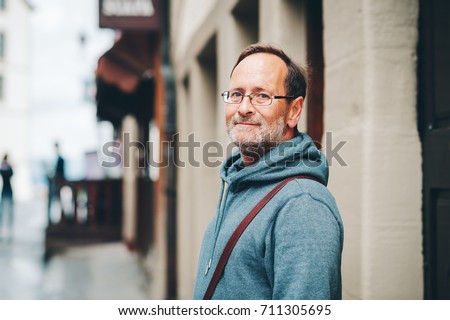 Outdoor portrait of 50 year old man wearing blue hoody and eyeglasses Royalty-Free Stock Photo #711305695