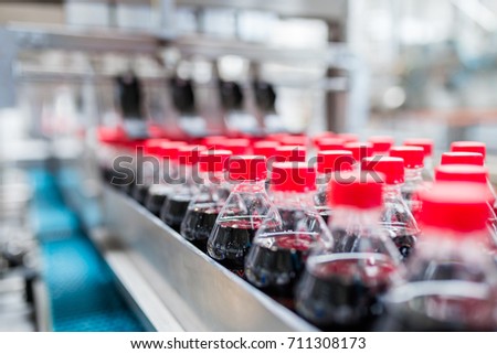 Bottling factory - Black juice bottling line for processing and bottling juice into bottles. Selective focus.  Royalty-Free Stock Photo #711308173
