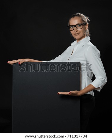 Young confident woman portrait of a confident businesswoman showing presentation, pointing placard black background. Ideal for banners, registration forms, presentation, landings, presenting concept.