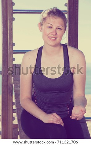 Fitness woman relaxing after workout outdoors on background with smooth sea