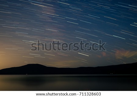 Timelaps of stars in the blue sky. Mountains, water. Long exposure. Astrophotography
