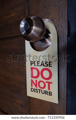 Closed door of hotel room with warning please do not disturb sign
